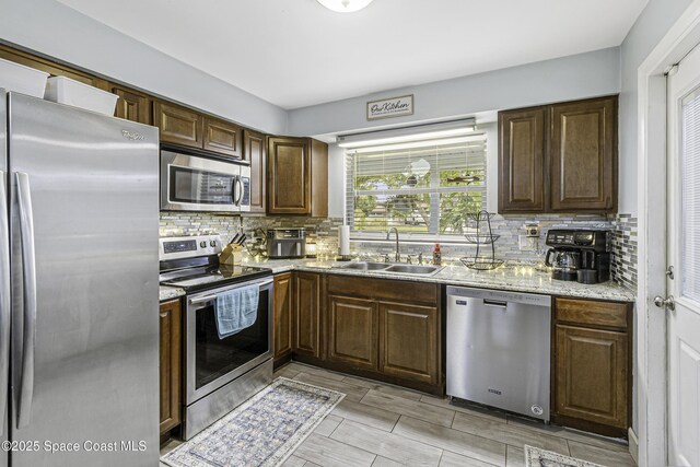 449 Amity Ave, Cocoa, FL 32927 - kitchen with stainless steel appliances, backsplash, light stone countertops, and dark brown cabinetry