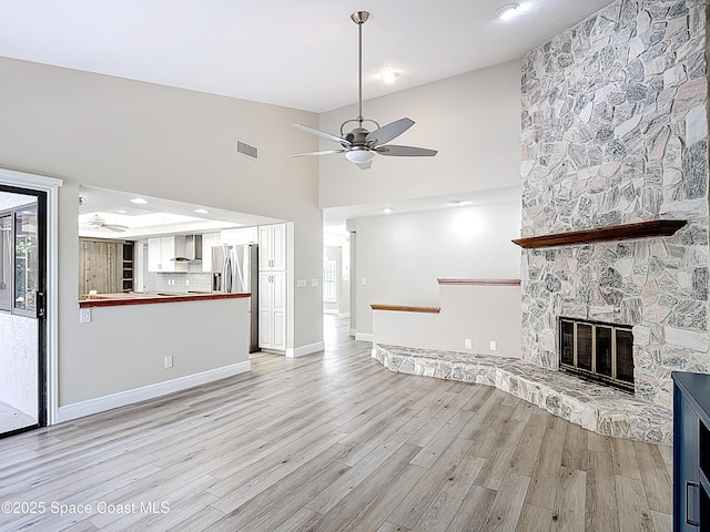 3090 Rio Pino S, Indialantic, FL 32903 - unfurnished living room with a ceiling fan, light wood-type flooring, a stone fireplace, and a towering ceiling
