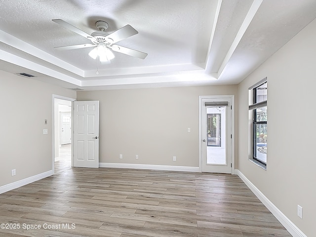3090 Rio Pino S, Indialantic, FL 32903 - empty room with a raised ceiling, ceiling fan, light wood-style floors, and a textured ceiling