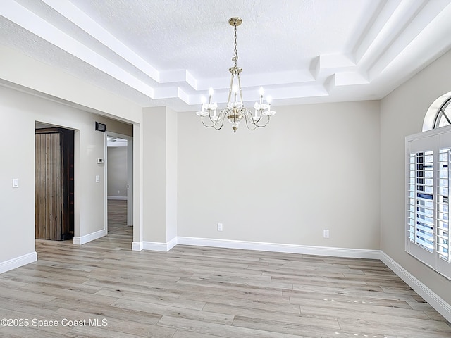 3090 Rio Pino S, Indialantic, FL 32903 - unfurnished room with a chandelier, a tray ceiling, light wood-type flooring, and a textured ceiling