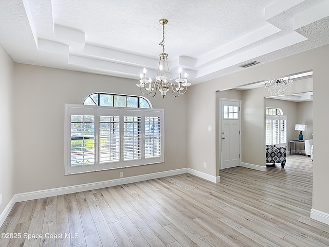 3090 Rio Pino S, Indialantic, FL 32903 - spare room featuring a raised ceiling, a chandelier, a textured ceiling, and light wood finished floors