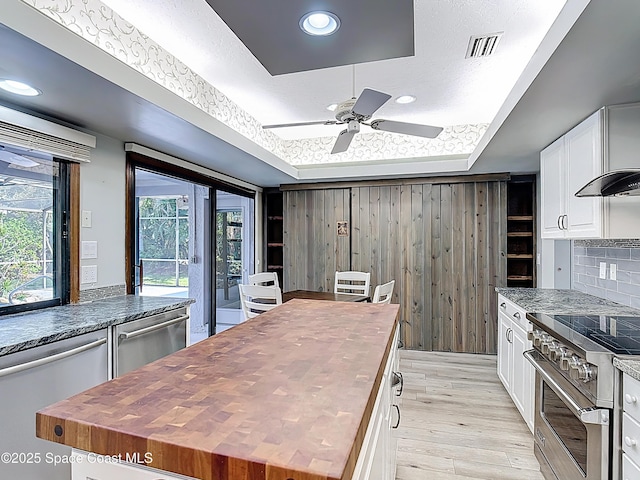 3090 Rio Pino S, Indialantic, FL 32903 - kitchen with butcher block countertops, stainless steel appliances, a tray ceiling, light wood-type flooring, and white cabinets