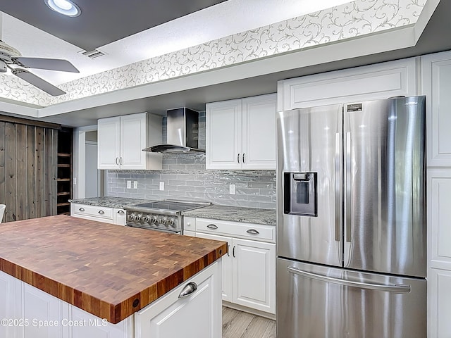3090 Rio Pino S, Indialantic, FL 32903 - kitchen featuring appliances with stainless steel finishes, butcher block countertops, wall chimney exhaust hood, a ceiling fan, and white cabinetry