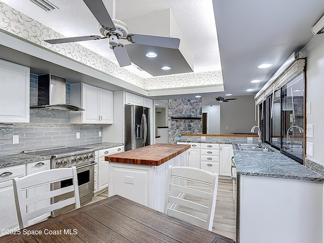 3090 Rio Pino S, Indialantic, FL 32903 - kitchen featuring butcher block counters, wall chimney range hood, appliances with stainless steel finishes, ceiling fan, and recessed lighting