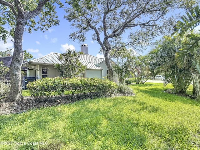 3090 Rio Pino S, Indialantic, FL 32903 - view of side of home featuring a standing seam roof, a metal roof, a chimney, stucco siding, and a yard