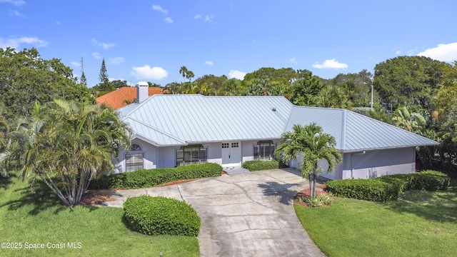 3090 Rio Pino S, Indialantic, FL 32903 - ranch-style home with concrete driveway, a front lawn, a chimney, a garage, and stucco siding