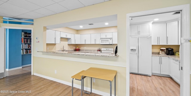 1890 N Atlantic Ave Unit A501, Cocoa Beach, FL 32931 - kitchen featuring white appliances, light wood finished floors, white cabinetry, and recessed lighting
