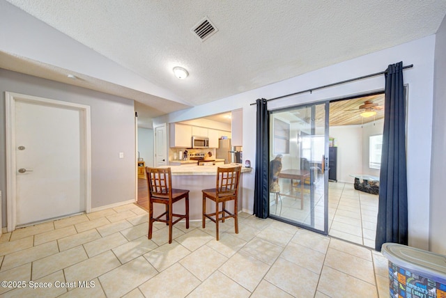 2169 Wagonwheel Ave SE, Palm Bay, FL 32909 - dining area with lofted ceiling, light tile patterned floors, and a textured ceiling