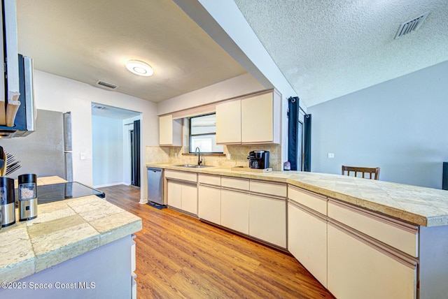 2169 Wagonwheel Ave SE, Palm Bay, FL 32909 - kitchen featuring stainless steel appliances, a peninsula, tile countertops, tasteful backsplash, and a textured ceiling