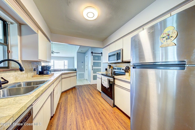 2169 Wagonwheel Ave SE, Palm Bay, FL 32909 - kitchen featuring stainless steel appliances, white cabinetry, light wood-style floors, and backsplash