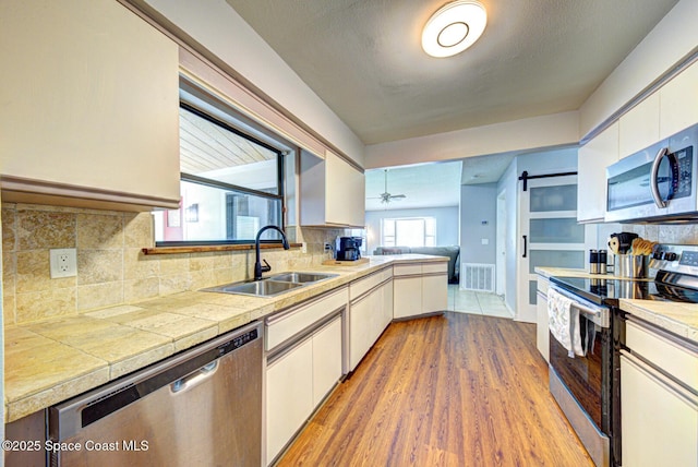 2169 Wagonwheel Ave SE, Palm Bay, FL 32909 - kitchen with stainless steel appliances, white cabinetry, tasteful backsplash, and light wood finished floors