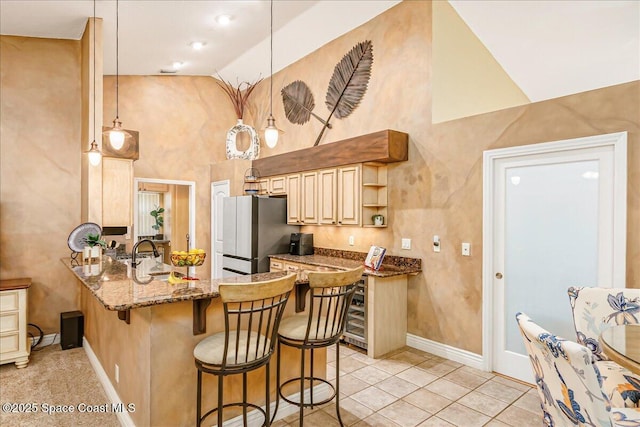 970 Pelican Ln, Rockledge, FL 32955 - kitchen featuring freestanding refrigerator, high vaulted ceiling, a kitchen bar, a peninsula, and dark stone countertops