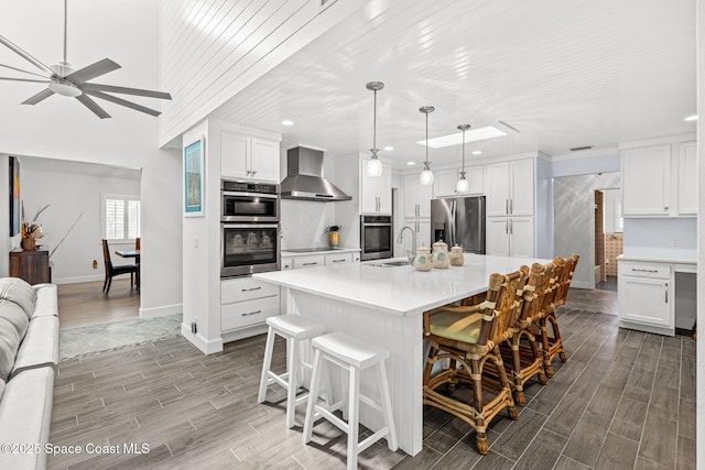 2945 Newfound Harbor Dr, Merritt Island, FL 32952 - kitchen with appliances with stainless steel finishes, wall chimney exhaust hood, wood tiled floors, a ceiling fan, and recessed lighting