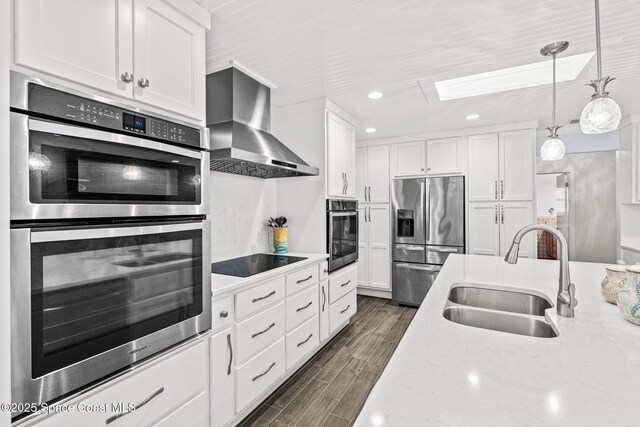 2945 Newfound Harbor Dr, Merritt Island, FL 32952 - kitchen featuring stainless steel appliances, wall chimney range hood, a skylight, white cabinetry, and recessed lighting