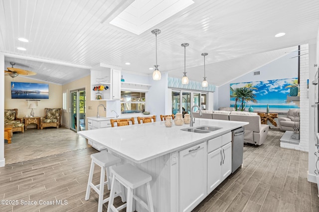 2945 Newfound Harbor Dr, Merritt Island, FL 32952 - kitchen featuring open floor plan, vaulted ceiling, a skylight, light wood-style floors, and white cabinetry