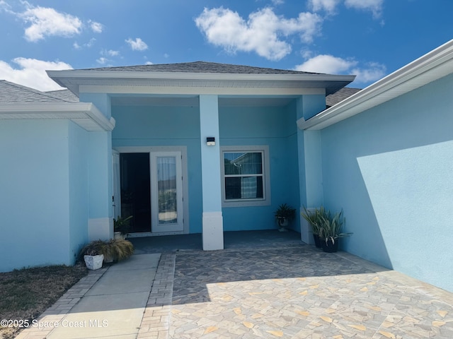 1305 Rabbit Street Se Port Malabar Unit 22, Palm Bay, FL 32909 - doorway to property with stucco siding, roof with shingles, and a patio area