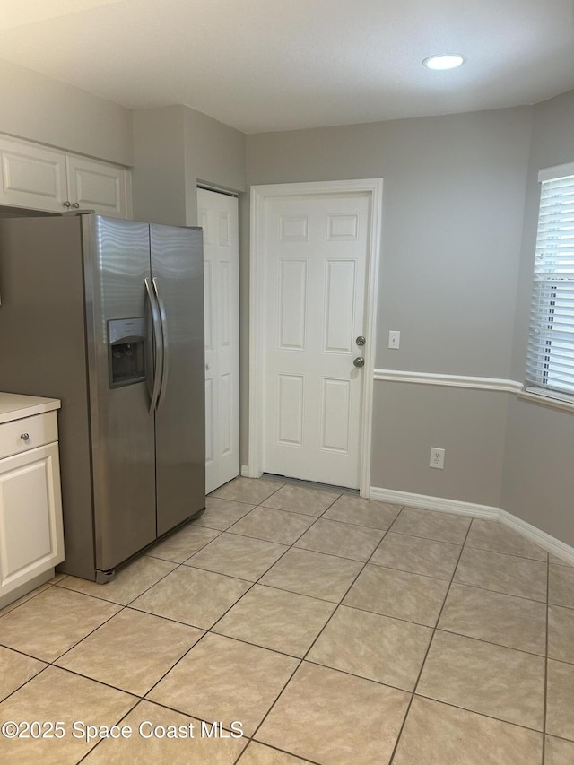 537 6th St, Vero Beach, FL 32962 - kitchen with stainless steel refrigerator with ice dispenser, white cabinetry, light tile patterned floors, and light countertops