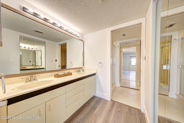 3609 S Banana River Blvd Unit C511, Cocoa Beach, FL 32931 - bathroom featuring wood finished floors, double vanity, a shower stall, and a textured ceiling