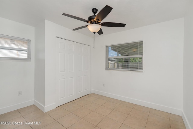 2515 Andrews Ave, Melbourne, FL 32935 - unfurnished bedroom featuring multiple windows, a closet, light tile patterned floors, and ceiling fan