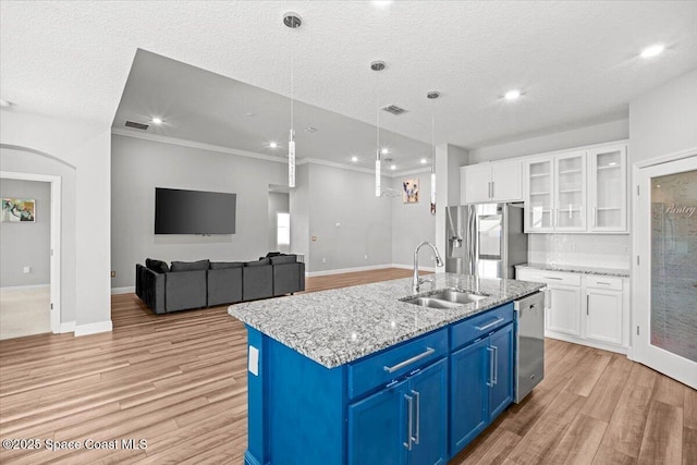 922 Raleigh Rd SE, Palm Bay, FL 32909 - kitchen featuring stainless steel appliances, blue cabinets, light wood-style floors, white cabinetry, and a kitchen island with sink