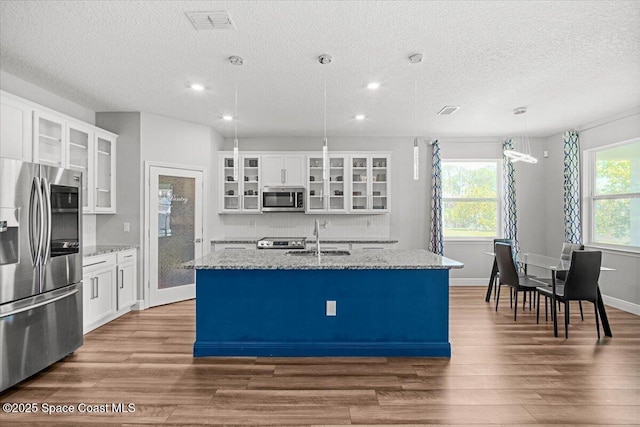 922 Raleigh Rd SE, Palm Bay, FL 32909 - kitchen with stainless steel appliances, a textured ceiling, a center island with sink, wood finished floors, and recessed lighting