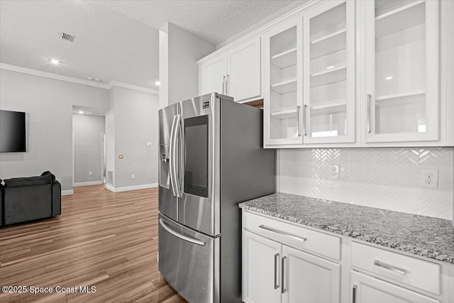 922 Raleigh Rd SE, Palm Bay, FL 32909 - kitchen featuring stainless steel refrigerator with ice dispenser, white cabinetry, tasteful backsplash, light wood-style flooring, and light stone counters