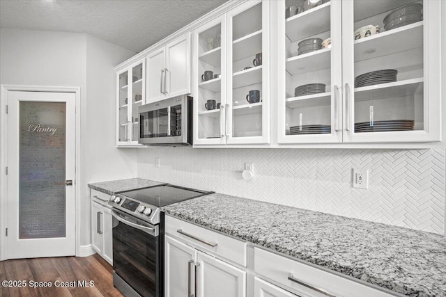 922 Raleigh Rd SE, Palm Bay, FL 32909 - kitchen with stainless steel appliances, light stone counters, white cabinetry, glass insert cabinets, and backsplash