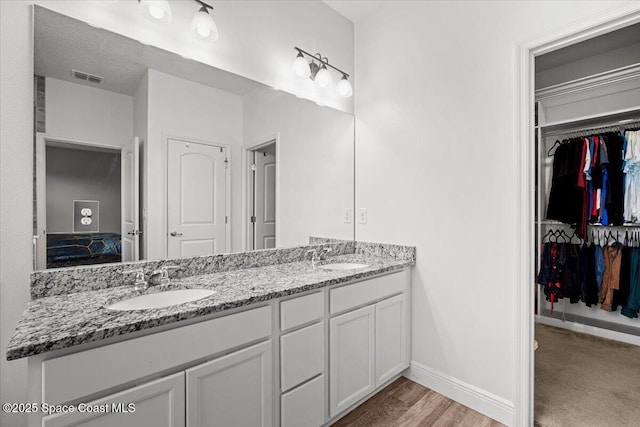922 Raleigh Rd SE, Palm Bay, FL 32909 - ensuite bathroom with double vanity, a walk in closet, and wood finished floors