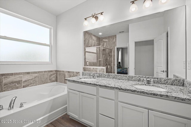 922 Raleigh Rd SE, Palm Bay, FL 32909 - full bathroom with double vanity, a stall shower, a garden tub, and wood finished floors