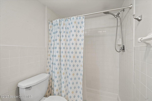 3170 N Atlantic Ave Unit 412, Cocoa Beach, FL 32931 - bathroom with tiled shower, tile walls, and a wainscoted wall