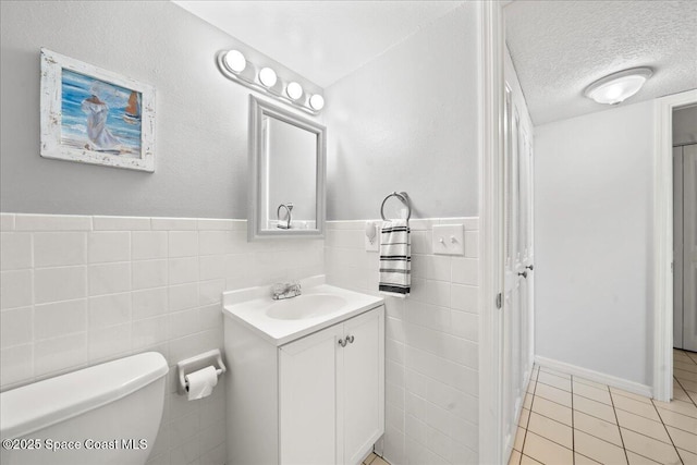 3170 N Atlantic Ave Unit 412, Cocoa Beach, FL 32931 - bathroom with vanity, tile walls, tile patterned floors, a wainscoted wall, and a textured ceiling