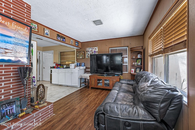 1714 Blanche Ave, Melbourne, FL 32934 - living area with light wood-style floors, a textured ceiling, and wood walls