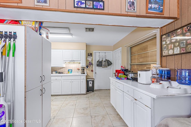 1714 Blanche Ave, Melbourne, FL 32934 - kitchen with light countertops, backsplash, white cabinets, and light tile patterned floors