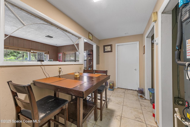 1714 Blanche Ave, Melbourne, FL 32934 - dining room with healthy amount of natural light, light tile patterned floors, and wood walls