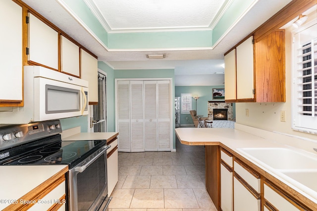 3461 Cove Ct, Melbourne, FL 32935 - kitchen featuring electric stove, white microwave, a stone fireplace, light countertops, and crown molding