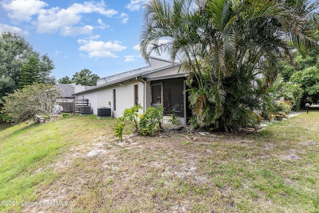 3461 Cove Ct, Melbourne, FL 32935 - rear view of property featuring stucco siding, a sunroom, and a yard