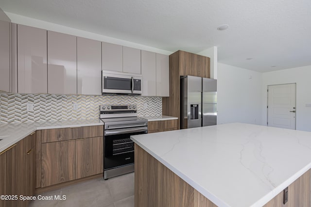 1326 Sagbloom St SE, Palm Bay, FL 32909 - kitchen with appliances with stainless steel finishes, modern cabinets, decorative backsplash, and light stone counters