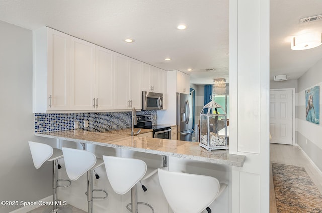 2880 S Atlantic Ave Unit 102, Cocoa Beach, FL 32931 - kitchen with appliances with stainless steel finishes, decorative backsplash, light stone countertops, white cabinetry, and recessed lighting