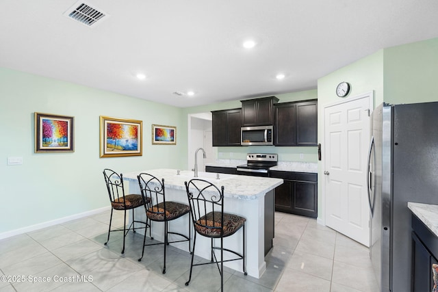 3724 Sandhill Crane Cir, Mims, FL 32754 - kitchen with appliances with stainless steel finishes, a kitchen bar, an island with sink, light tile patterned floors, and recessed lighting