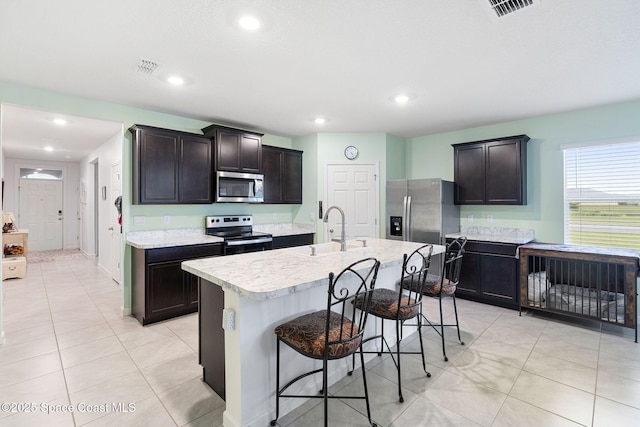 3724 Sandhill Crane Cir, Mims, FL 32754 - kitchen featuring stainless steel appliances, light countertops, a center island with sink, light tile patterned flooring, and a breakfast bar