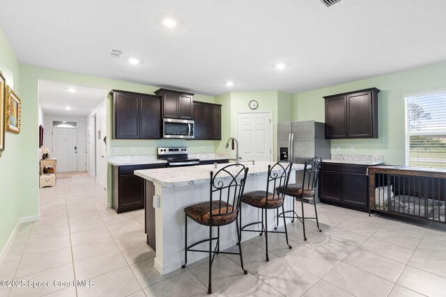 3724 Sandhill Crane Cir, Mims, FL 32754 - kitchen featuring stainless steel appliances, light countertops, a kitchen bar, light tile patterned floors, and a center island with sink