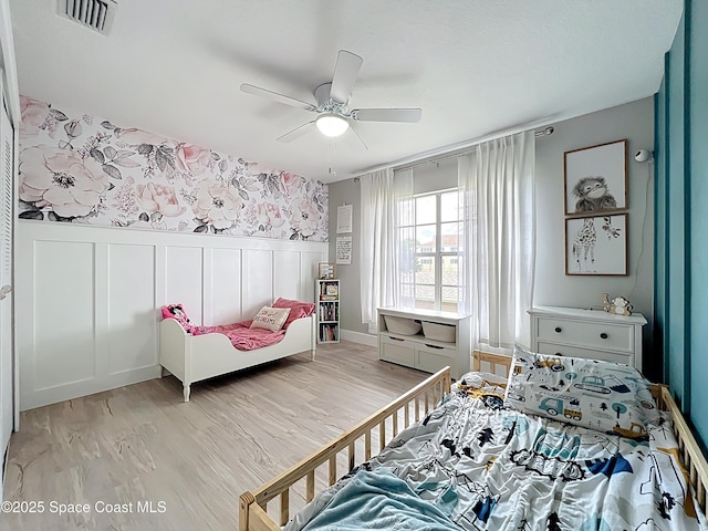 1870 Long Iron Dr Unit 1225, Rockledge, FL 32955 - bedroom with light wood-type flooring, wainscoting, a decorative wall, and a ceiling fan
