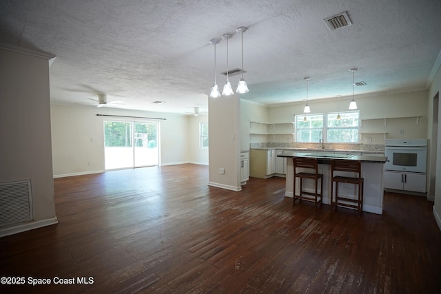 614 W Ct, Titusville, FL 32796 - kitchen with open floor plan, a textured ceiling, white oven, dark wood-type flooring, and white cabinets