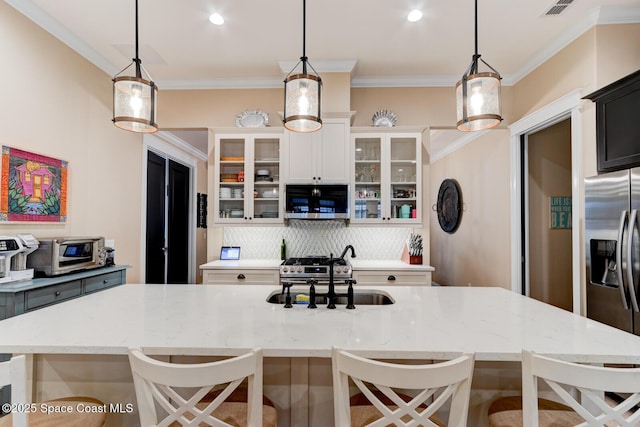 105 Azalea Cir, New Smyrna Beach, FL 32168 - kitchen with stainless steel appliances, ornamental molding, backsplash, a kitchen island with sink, and a breakfast bar
