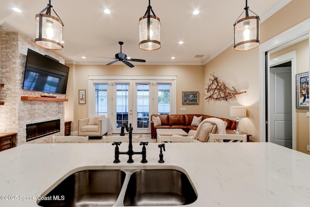 105 Azalea Cir, New Smyrna Beach, FL 32168 - kitchen with ceiling fan, open floor plan, a stone fireplace, light stone counters, and ornamental molding
