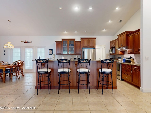 6025 Brabrook Ave, Grant, FL 32949 - kitchen with stainless steel appliances, under cabinet range hood, a kitchen bar, recessed lighting, and glass insert cabinets