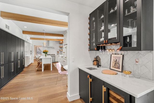 2600 N Riverside Dr, Indialantic, FL 32903 - indoor wet bar featuring tasteful backsplash, light wood finished floors, wall oven, decorative light fixtures, and wall chimney range hood