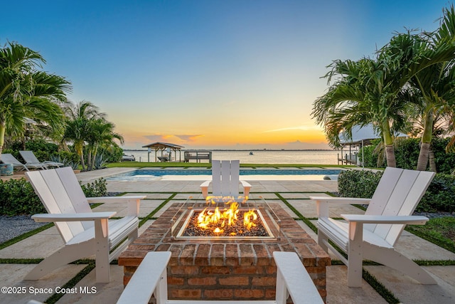 2600 N Riverside Dr, Indialantic, FL 32903 - patio terrace at dusk with an outdoor fire pit, an outdoor pool, a patio area, and a water view