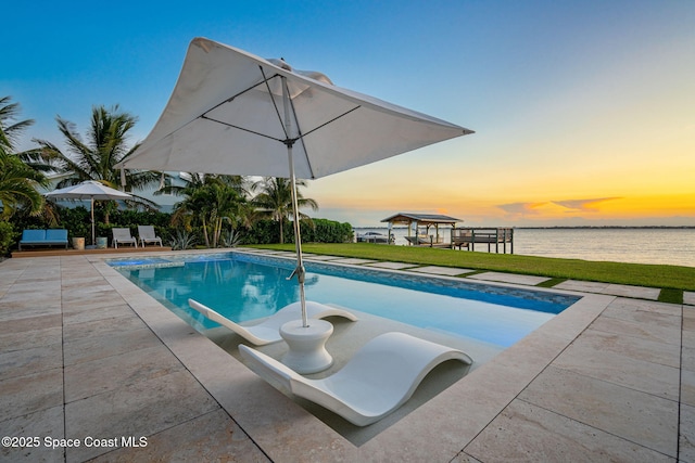 2600 N Riverside Dr, Indialantic, FL 32903 - pool at dusk featuring an outdoor pool, a patio, and a lawn