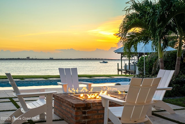 2600 N Riverside Dr, Indialantic, FL 32903 - pool at dusk featuring an outdoor fire pit, a water view, and an outdoor pool